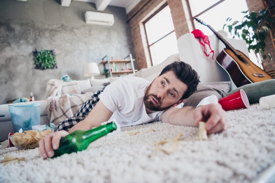 Muž vyčerpaný po nadměrném pití alkoholu, typické negativní účinky alkoholu jako únava, bolest hlavy a nevolnost