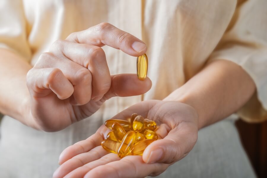 Ruce držící několik kapslí omega-3 rybího oleje – užívání doplňků stravy s omega 3 mastnými kyselinami pro podporu zdraví