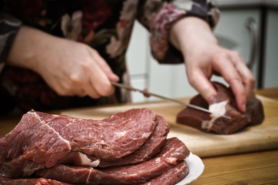 Krájení syrového hovězího masa – zdroj hemového železa v potravinách.